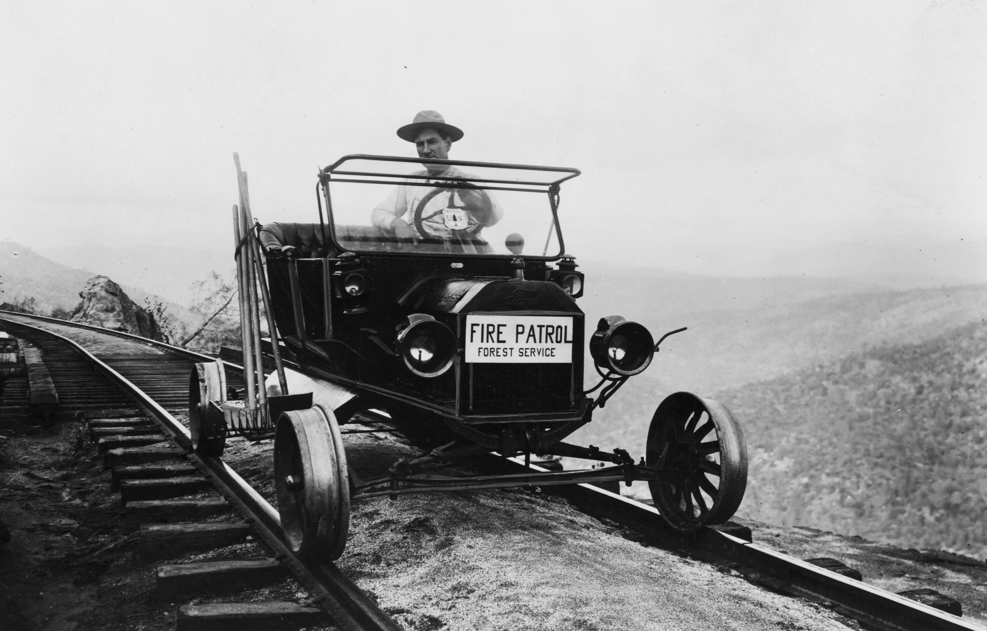 Man in vehicle of fire patrol forest service on railroad tracks in 1910